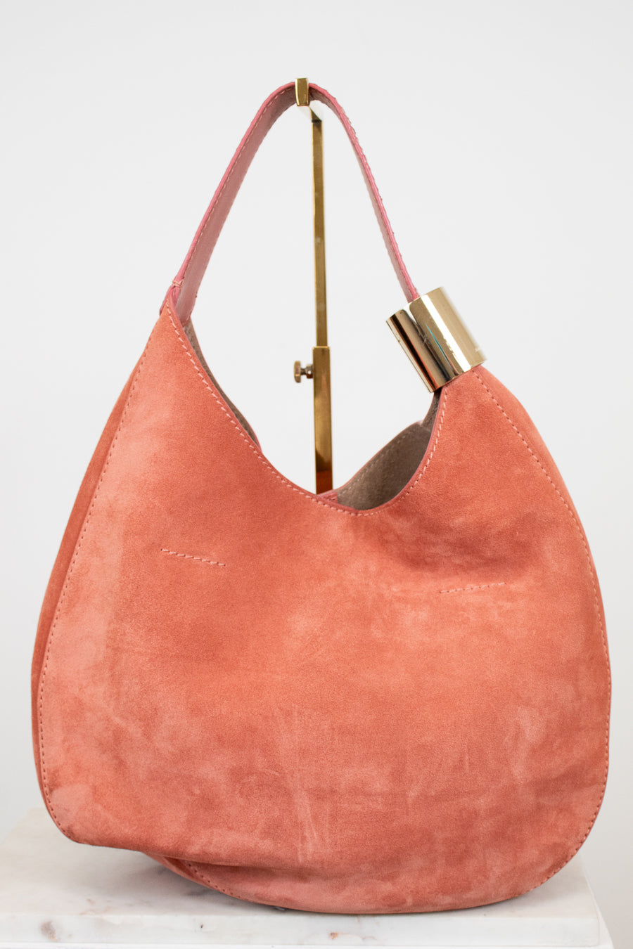 Pink handbag with gold accents on a white background