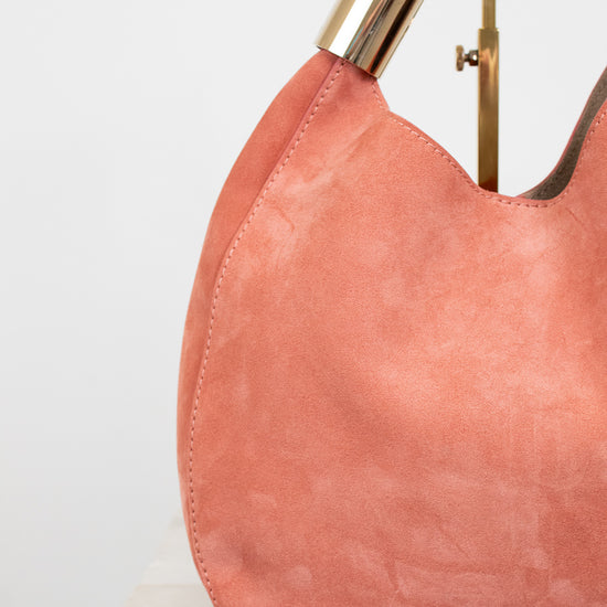 Pink handbag with gold handle on a white background