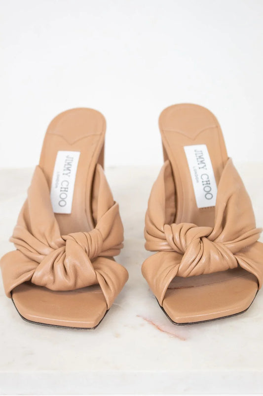 Pair of tan sandals with knotted design on a white background