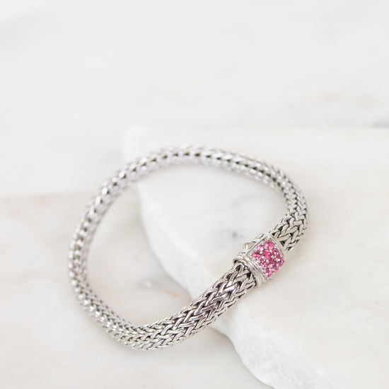 Silver bracelet with a pink stones on a white surface