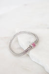 Silver bracelet with a pink stones on a white surface