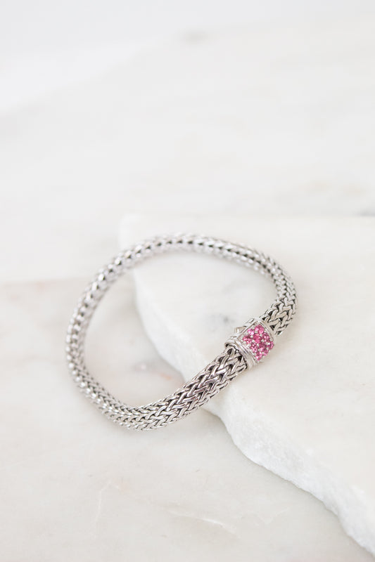 Silver bracelet with a pink stones on a white surface