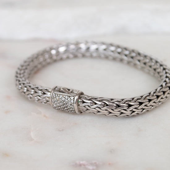 Silver braided bracelet with pave diamonds on a marble surface