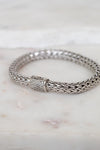 Silver braided bracelet with pave diamonds on a marble surface