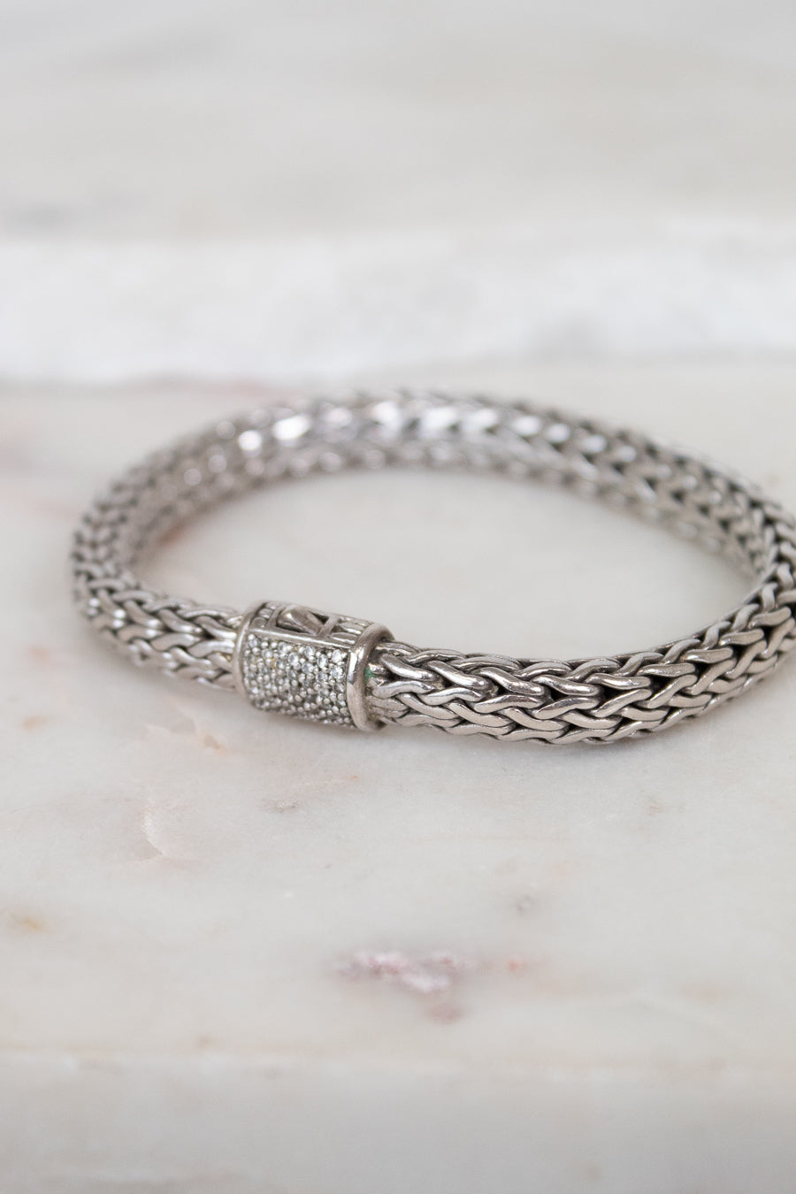 Silver braided bracelet with pave diamonds on a marble surface
