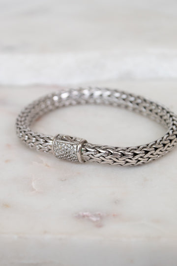 Silver braided bracelet with pave diamonds on a marble surface