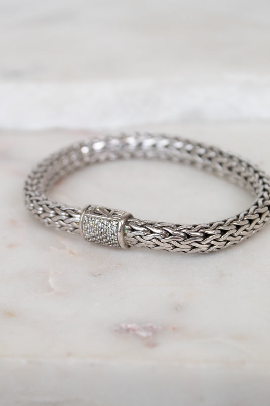 Silver braided bracelet with pave diamonds on a marble surface
