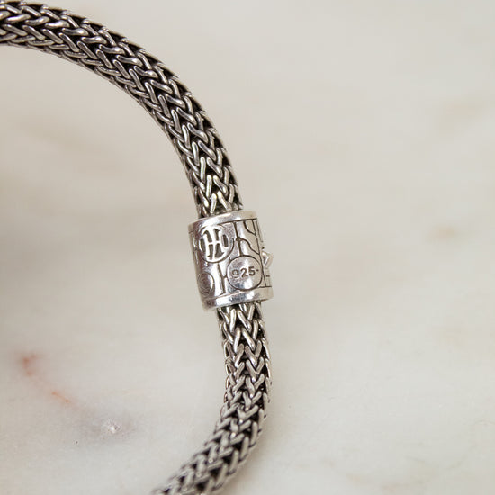Silver braided bracelet with a clasp on a marble surface