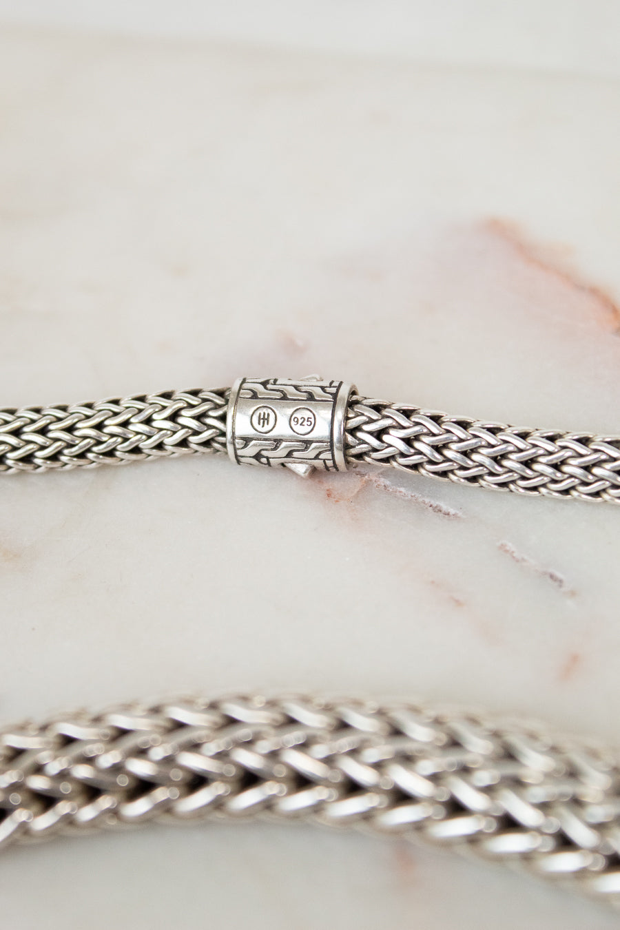 Close-up of a silver chain necklace on a marble surface