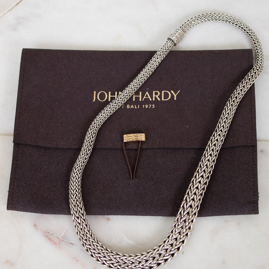 Silver chain necklace on a John Hardy pouch with a marble background