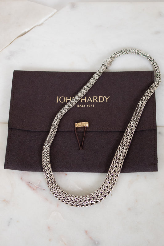 Silver chain necklace on a John Hardy pouch with a marble background