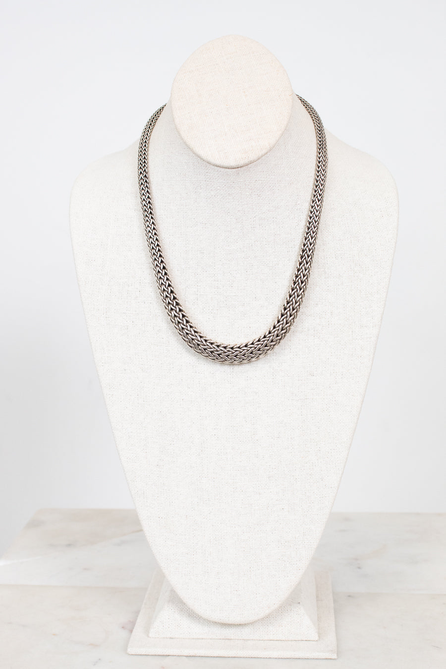 Silver chain necklace on a mannequin bust against a white background