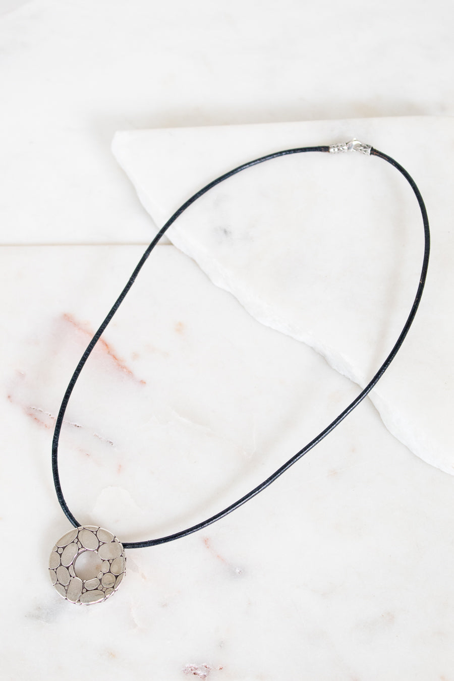 Necklace with a decorative pendant on a marble surface