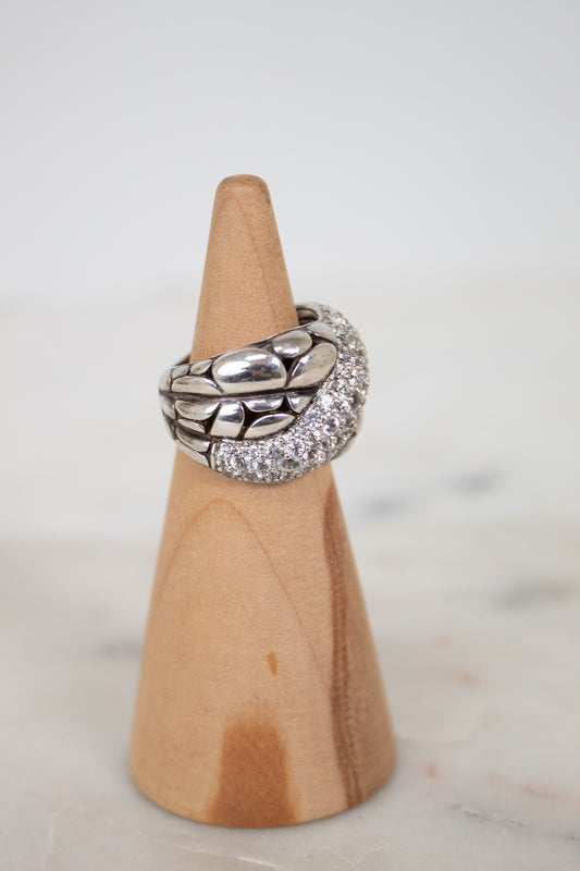 Silver ring with embedded stones on a wooden cone against a light background