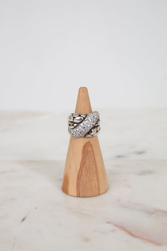 Wooden ring holder with a silver ring on a marble surface