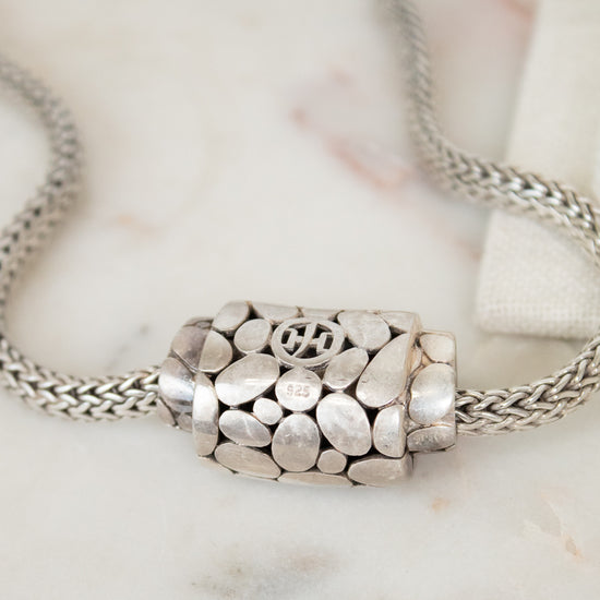 Silver necklace with a detailed pendant on a marble surface