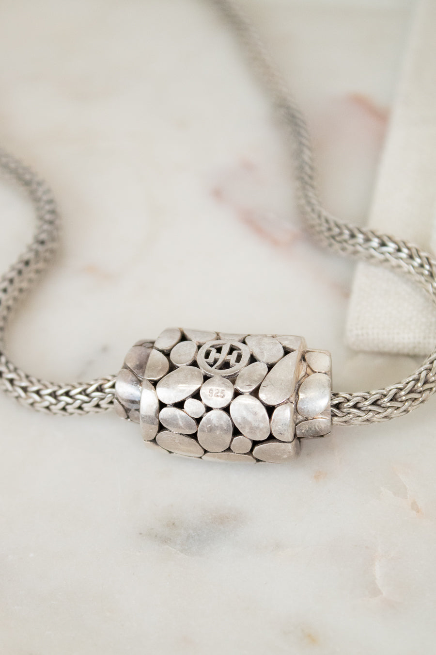 Silver necklace with a detailed pendant on a marble surface