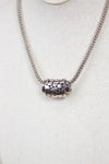 Silver necklace with a textured pendant on a light gray background