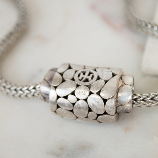 Silver necklace with a decorative pendant on a marble surface