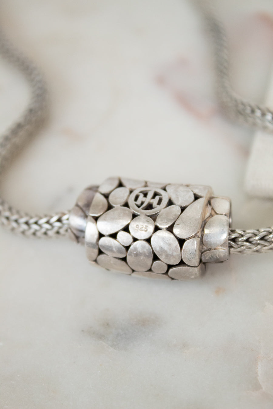 Silver necklace with a decorative pendant on a marble surface