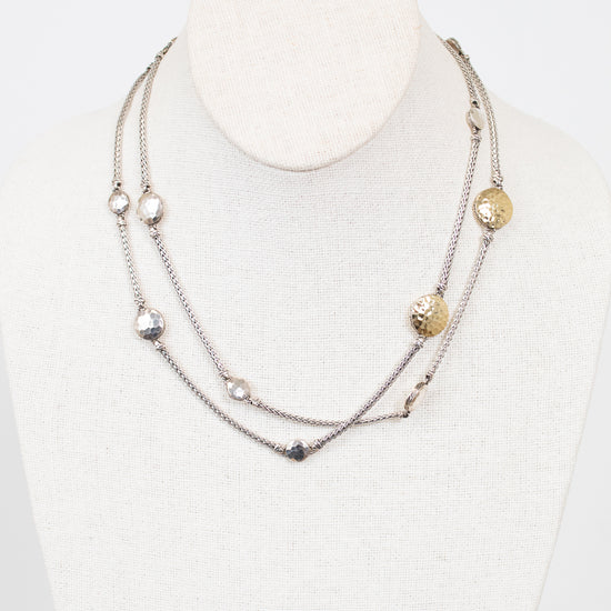 Multistrand necklace with various beads on a mannequin against a white background