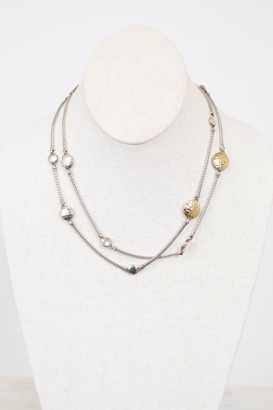 Multistrand necklace with various beads on a mannequin against a white background