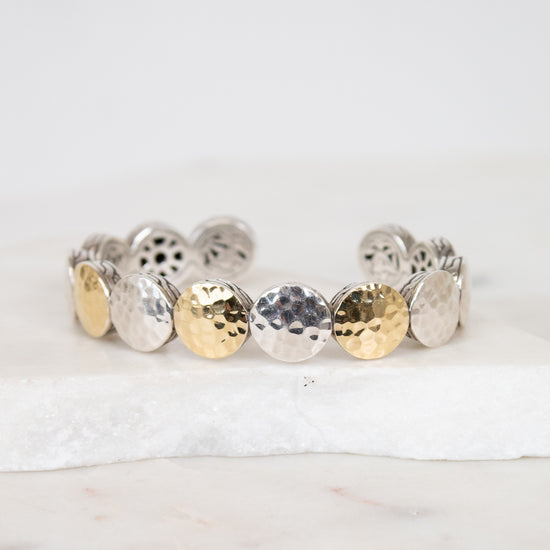 Bracelet with round, textured design in gold and silver on a white background