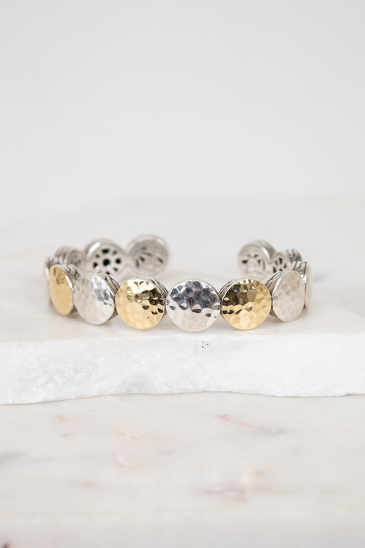 Bracelet with round, textured design in gold and silver on a white background