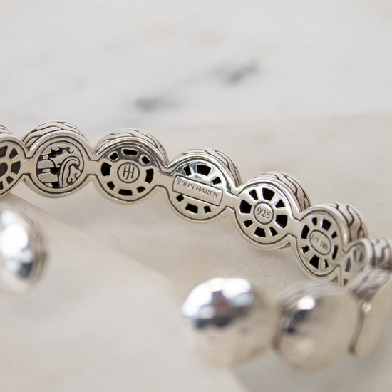 Silver bracelet with intricate design on a white background