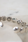 Silver bracelet with intricate design on a white background