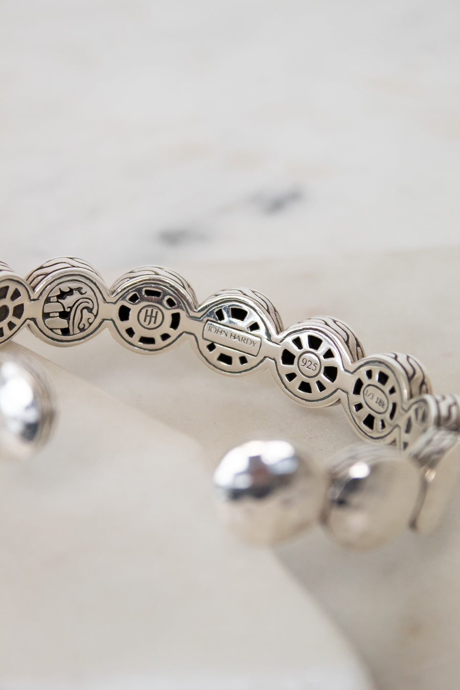 Silver bracelet with intricate design on a white background