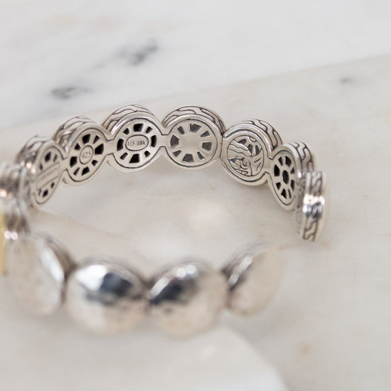 Silver bracelet with intricate design on a white marble surface