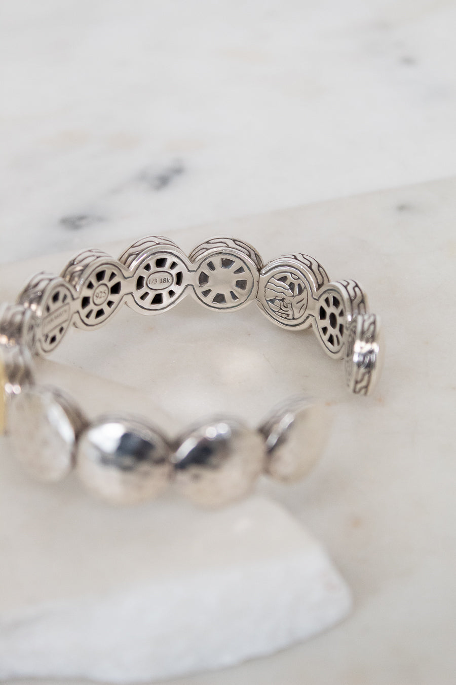Silver bracelet with intricate design on a white marble surface