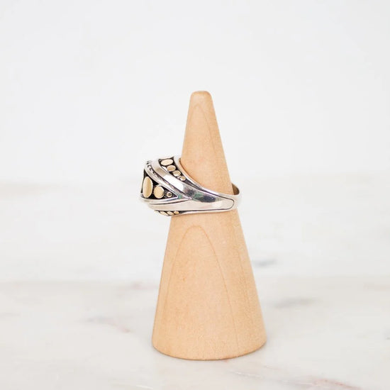 Silver ring on a wooden cone against a white background