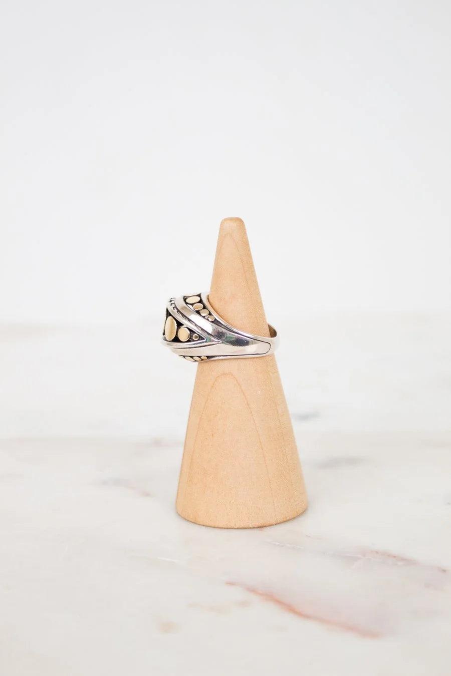 Silver ring on a wooden cone against a white background