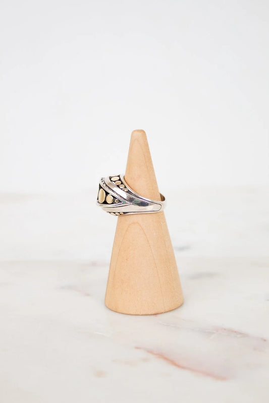 Silver ring on a wooden cone against a white background