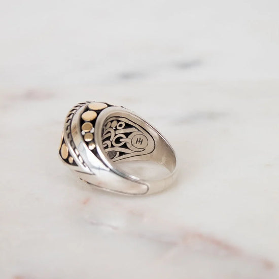 Silver ring with intricate design on a marble surface