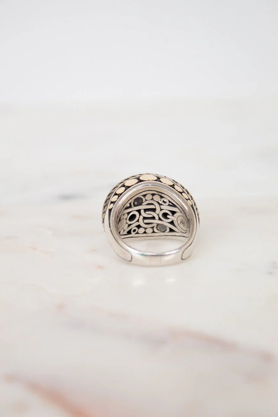 Silver ring with intricate design on a marble surface