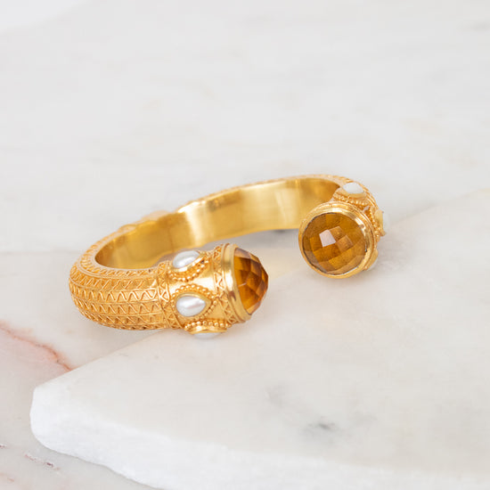 Gold bracelet with glass ends on a marble surface