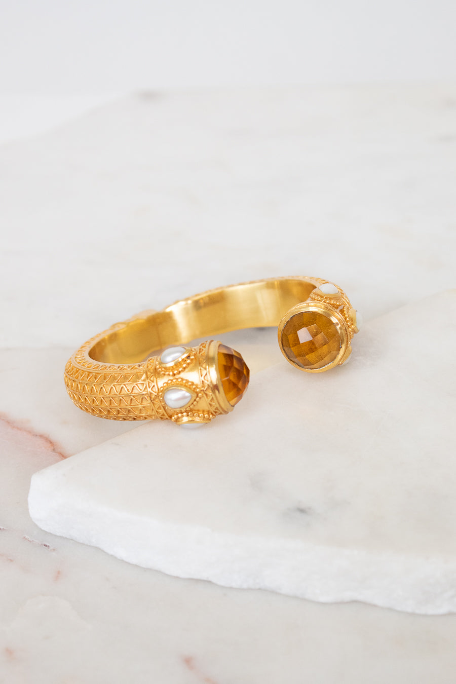 Gold bracelet with glass ends on a marble surface