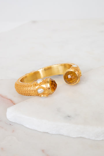 Gold bracelet with glass ends on a marble surface