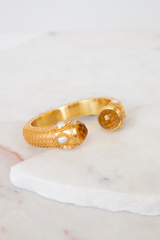 Gold bracelet with glass ends on a marble surface