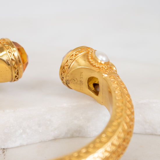 Gold bracelet with intricate design on a white surface