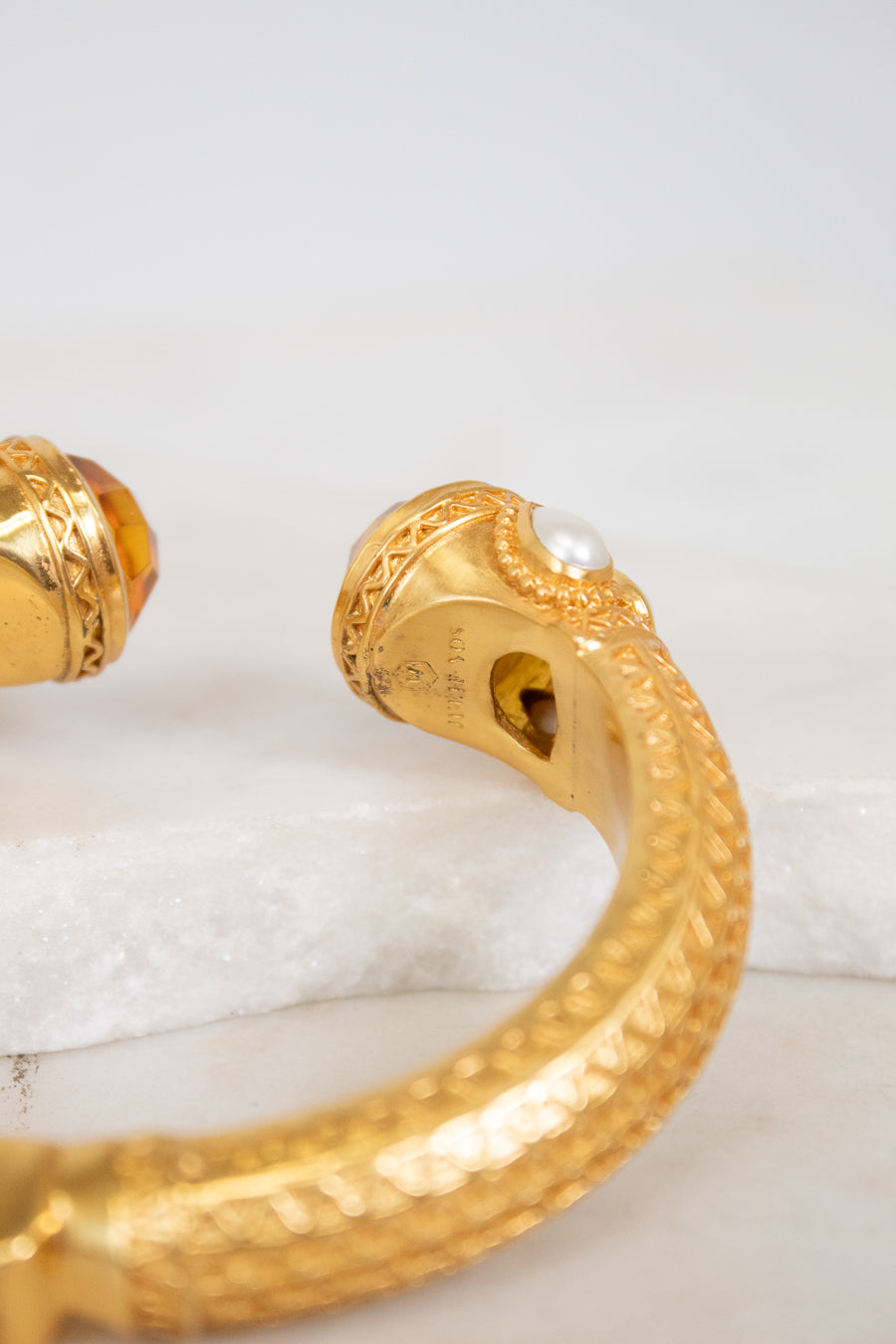 Gold bracelet with intricate design on a white surface