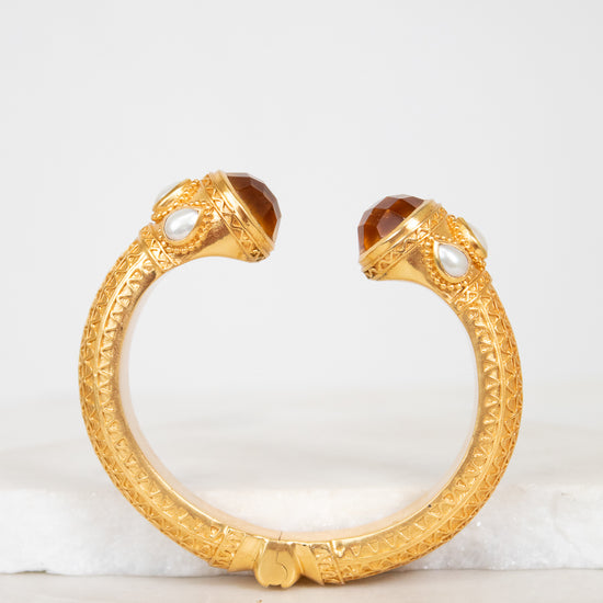 Gold bracelet with glass detail ends on a light background