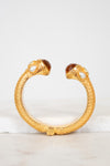 Gold bracelet with glass detail ends on a light background