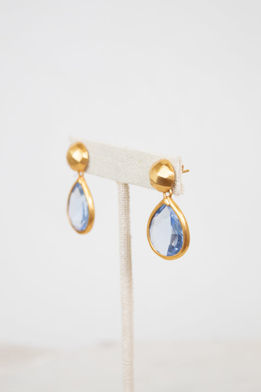 Gold-border earrings with blue teardrop-shaped stones on a white background