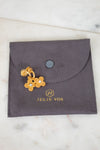 Gold floral earrings on a gray Julie Vos jewelry pouch.
