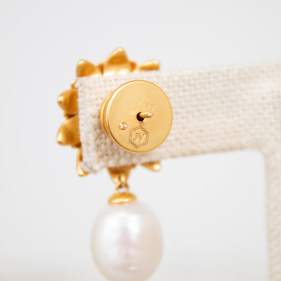 Gold earring with a pearl on a white background