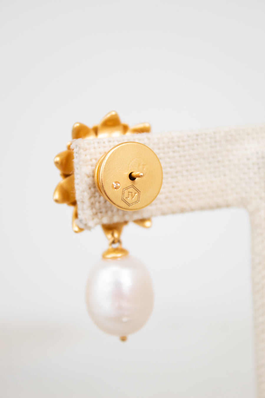 Gold earring with a pearl on a white background